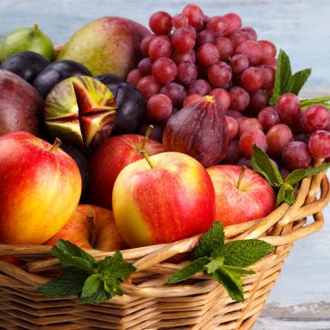 Basket of fresh organic fruits in the garden on rustic background